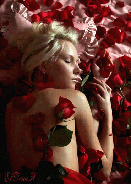 Девушка блондинка спит в постели с лепестками роз