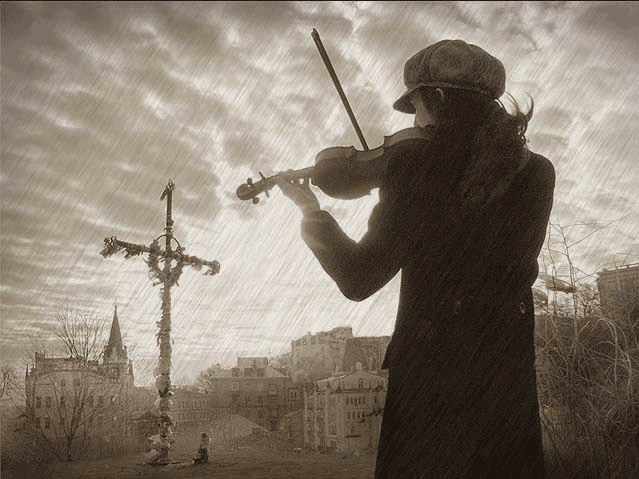 Скрипач со скрипкой стоит на улице под дождём