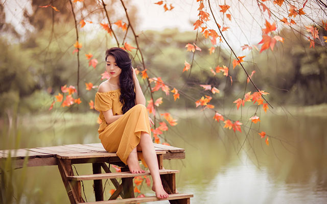 Красивая китаянка сидит возле пруда